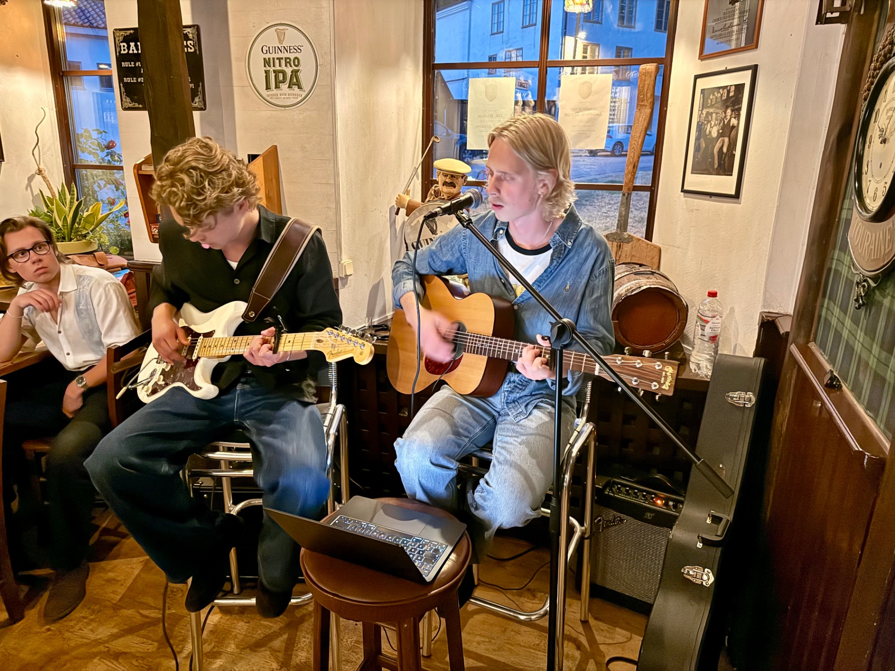 Blond spelar på pub med publik i bakgrunden