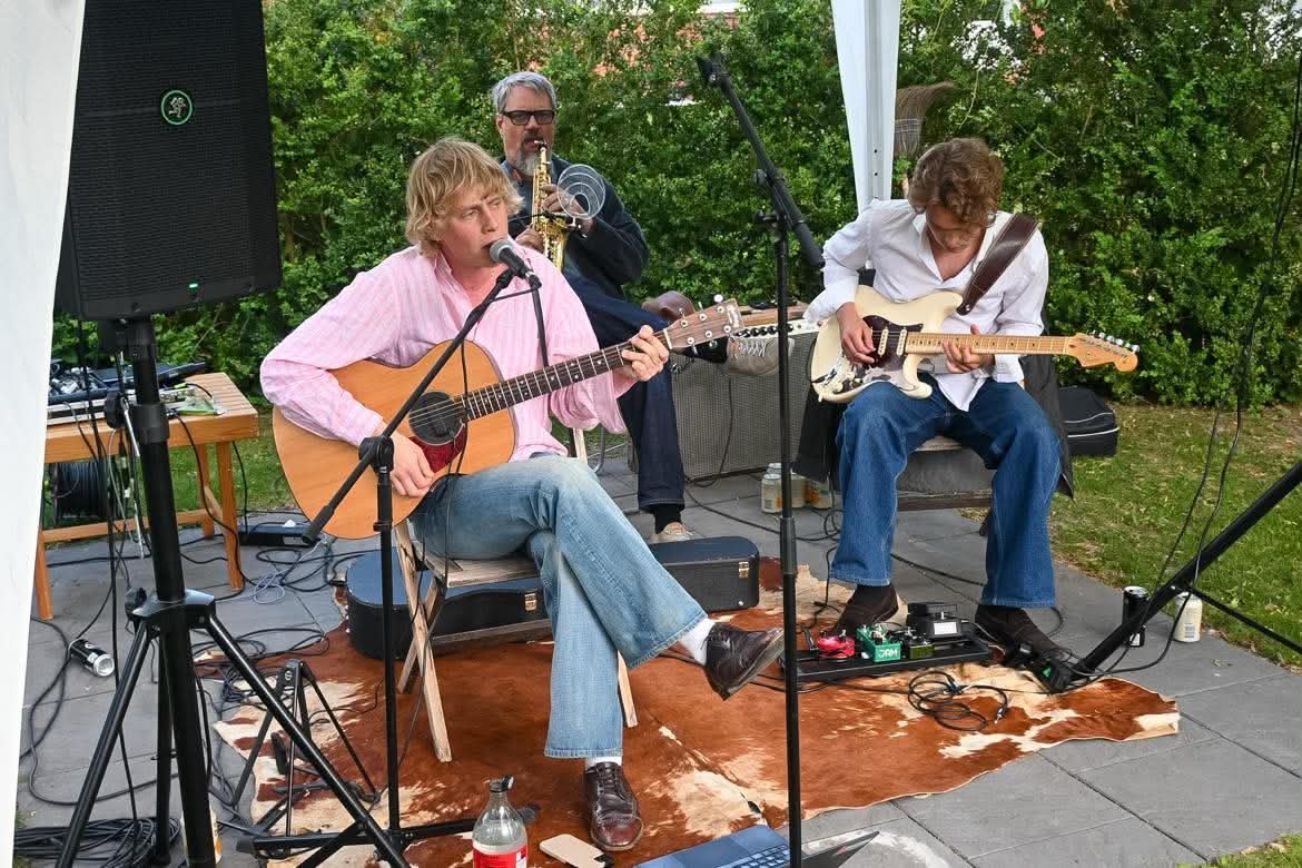 Blond live i trädgården med sång, gitarr och saxofon
