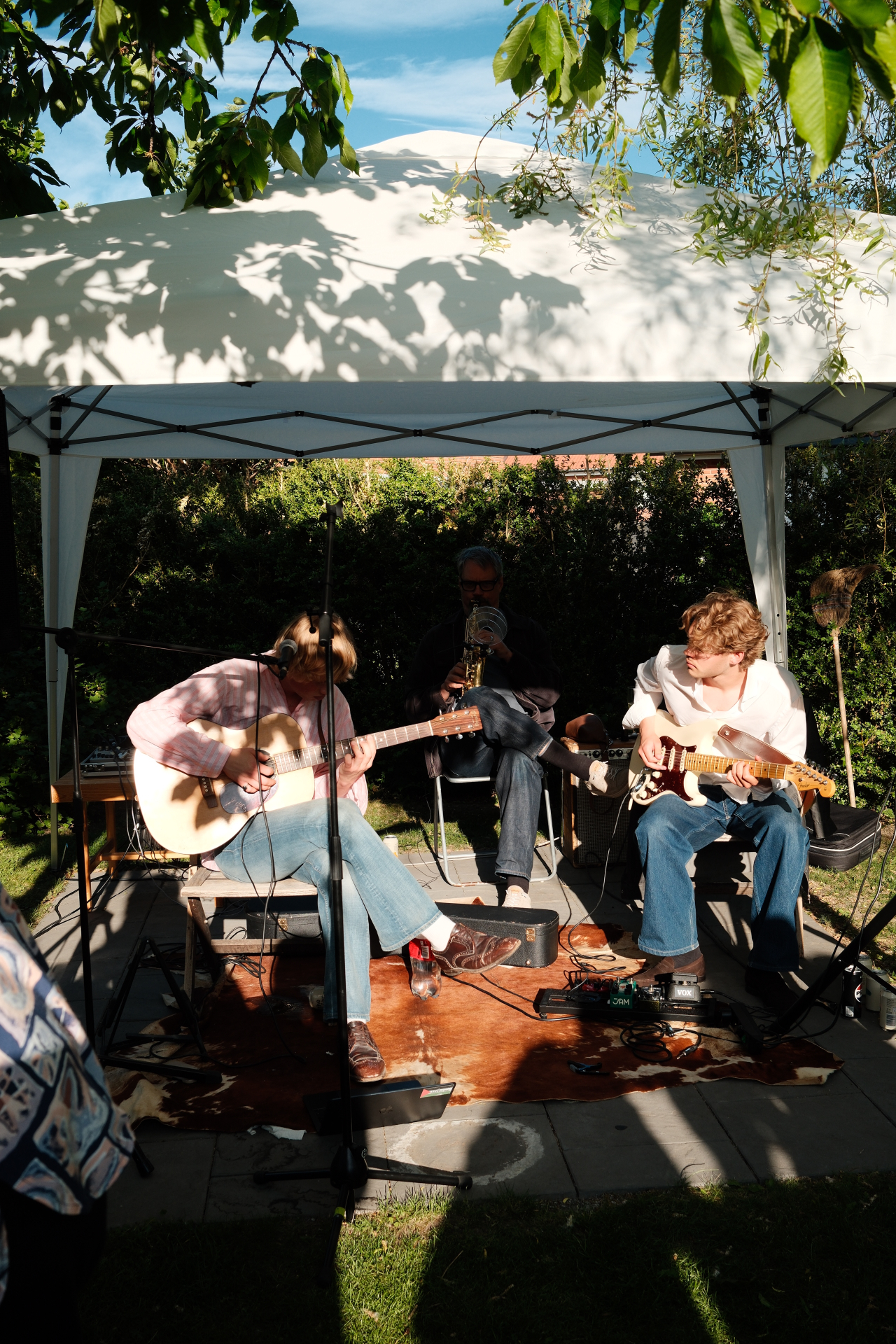 Blond live i trädgården under tält med saxofon och gitarrer